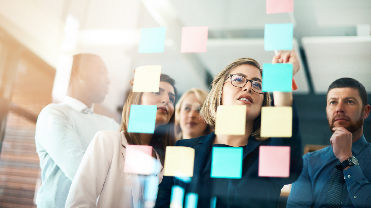 Planning, innovation and vision business meeting in a modern office, working on a business marketing strategy. Group, team or staff discussing with sticky notes a schedule for future project together.