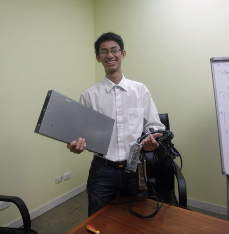Binh smiles in an office, holding a Cisco switch and power supply.