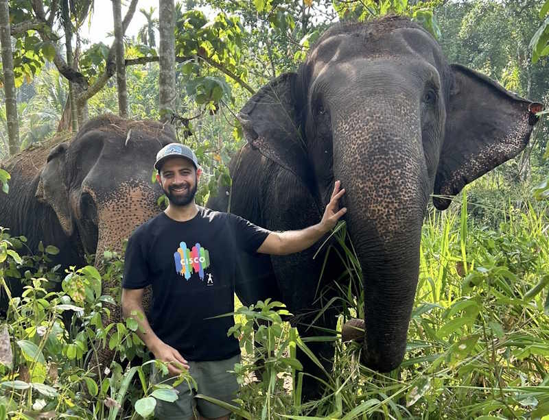 Sameer stands between two elephants.