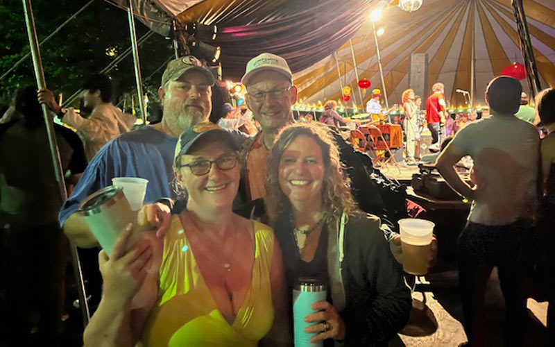 Four volunteers stand near stage with live music.