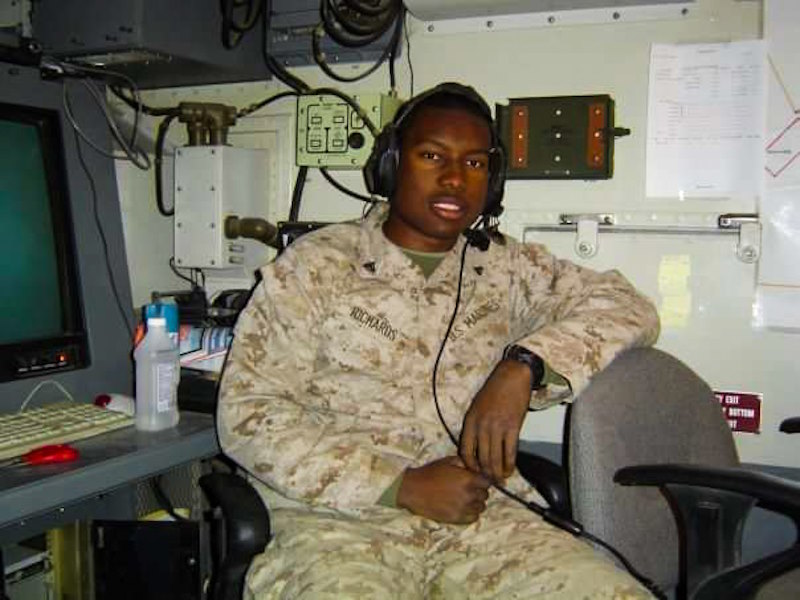 Andre as a soldier wears fatigues and headphones in an operations center.