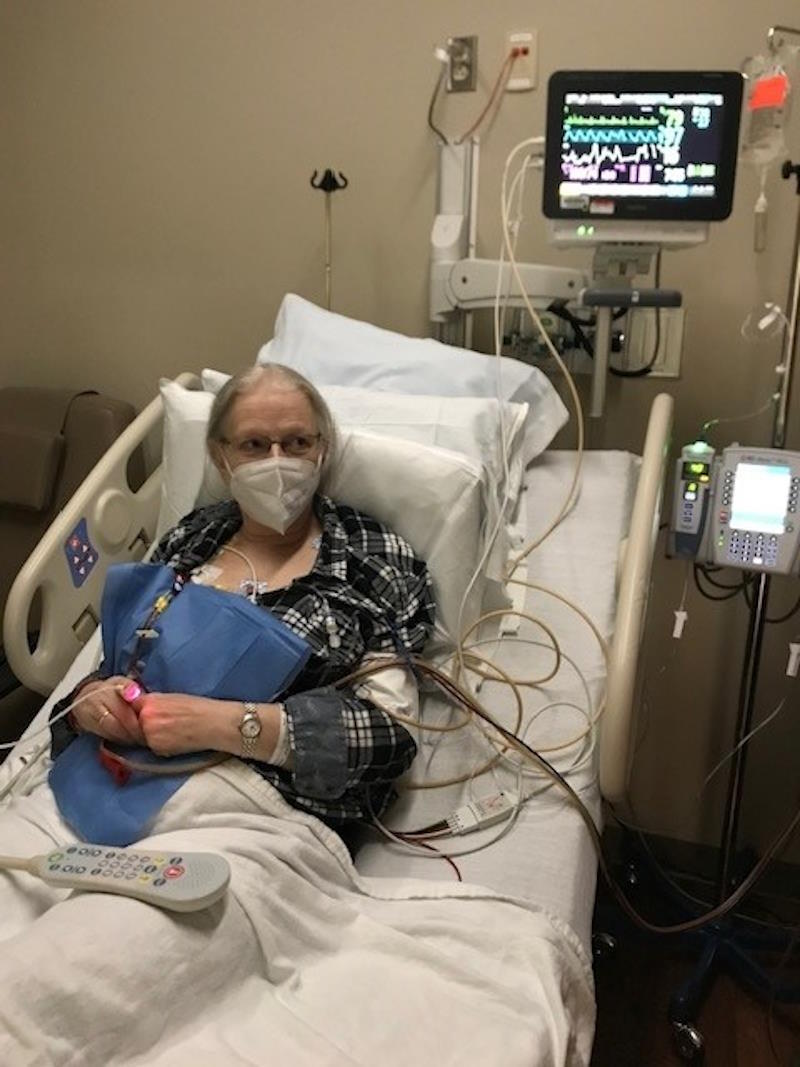 Catherine sits in a hospital bed next to a stem cell harvesting machine.