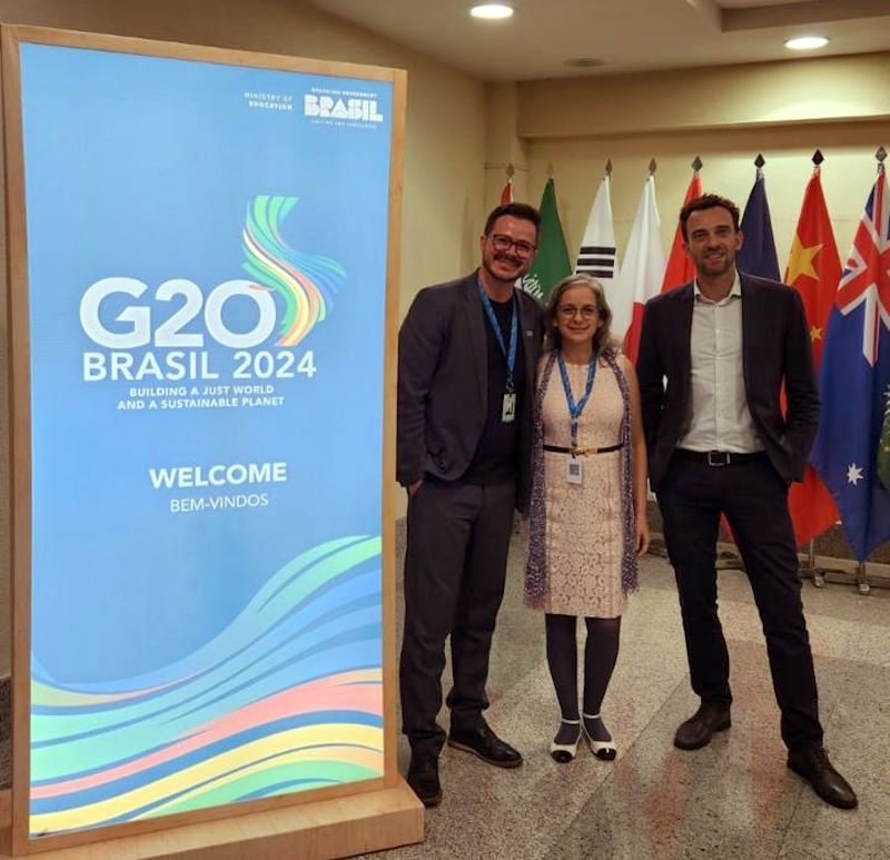 Gabriel, Wisley, and Cristina stand by a G20 Brasil 2024 sign.