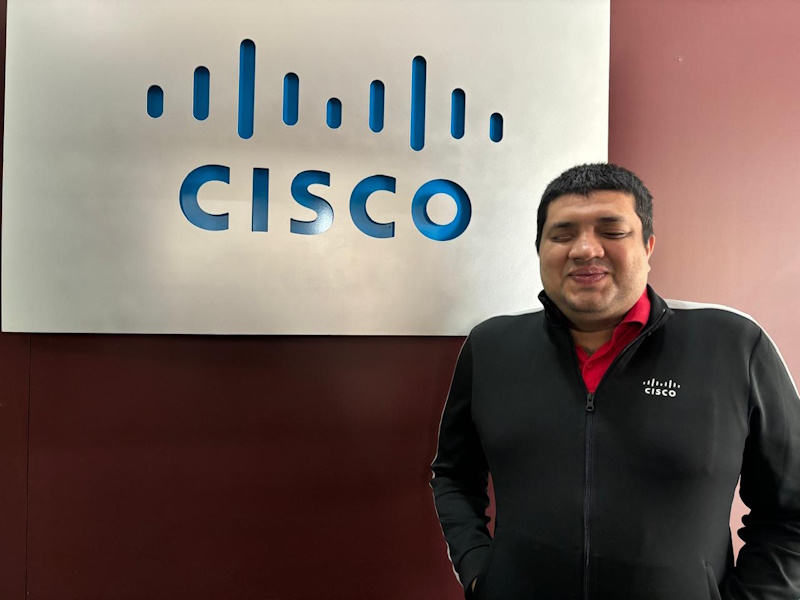 A man stands in front of the Cisco logo at the Bangalore office.