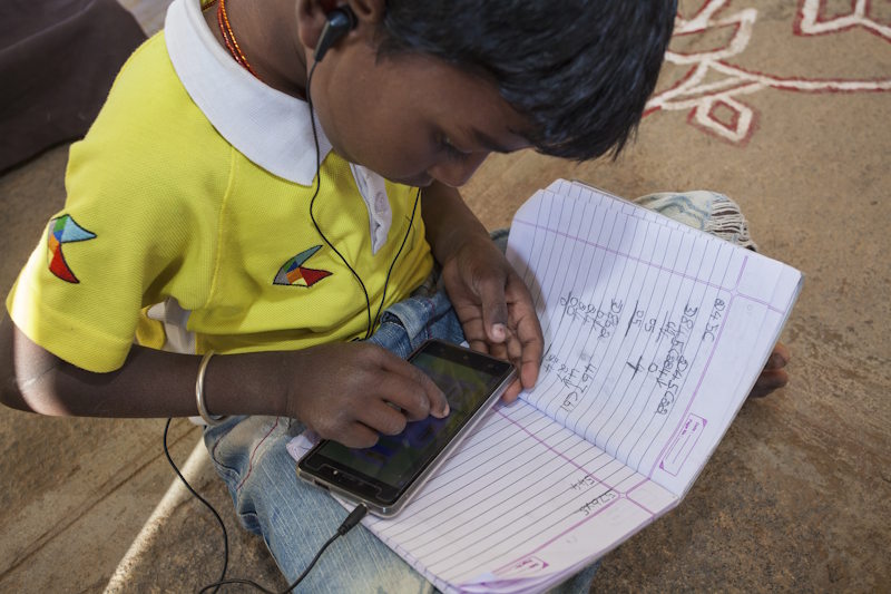 A woman wearing a sari holds a smart phone.