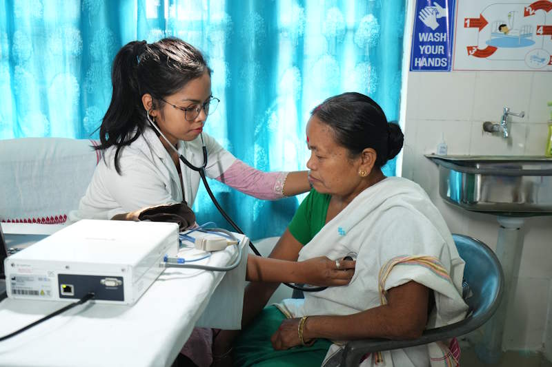 A doctor using technology while checking a patient with a stethoscope. 