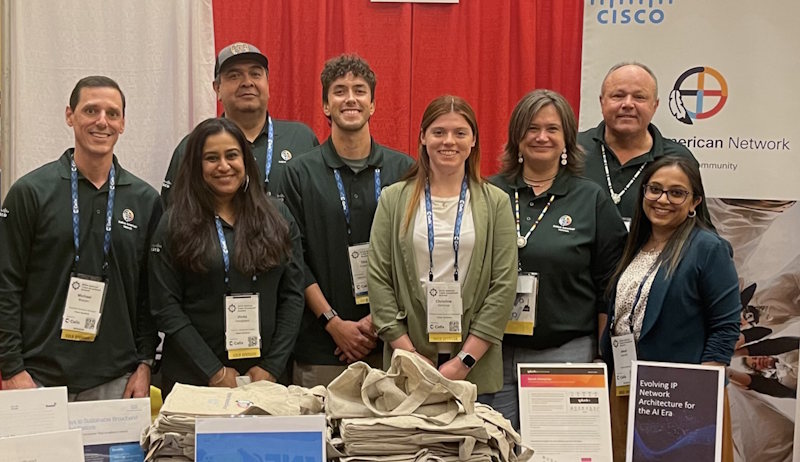 A group of people wearing conference lanyards, smiling.
