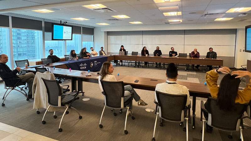 A large group sits around a table in a conference room.