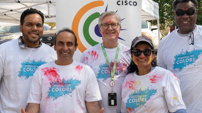 Five people wearing white t-shirts splattered with colorful powder, standing in front of a banner with the ICON logo. 