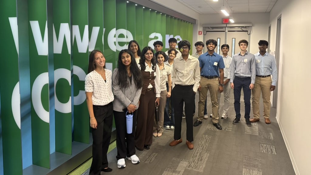 Students stand together in a corridor next to a We Are Cisco sign.