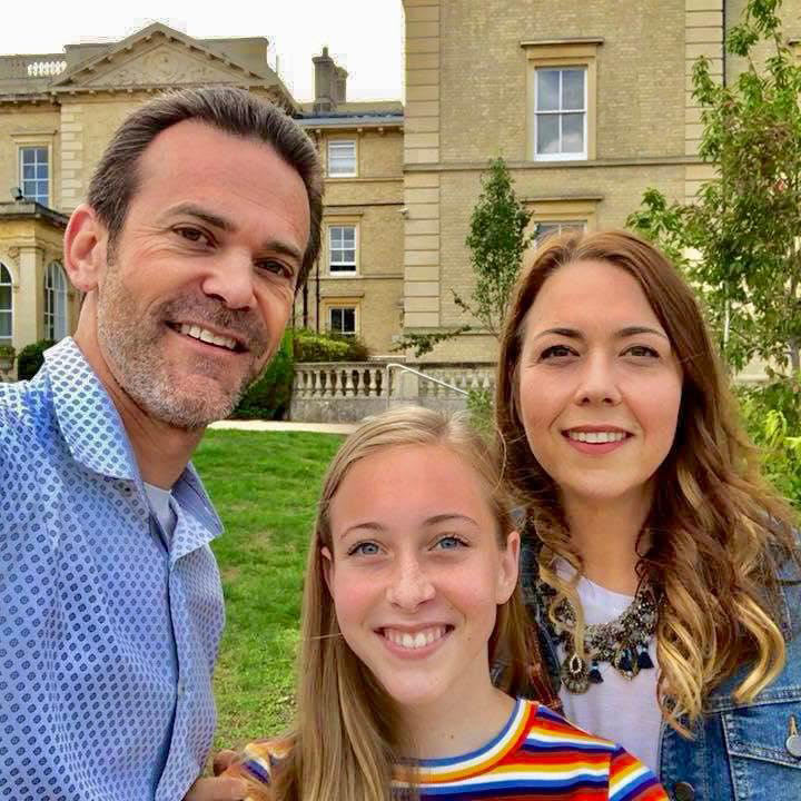 Kevin poses with his family in front of a historic building.