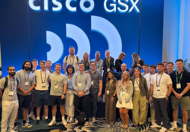 A large group of conference attendees stands together in front of a Cisco GSX backdrop.